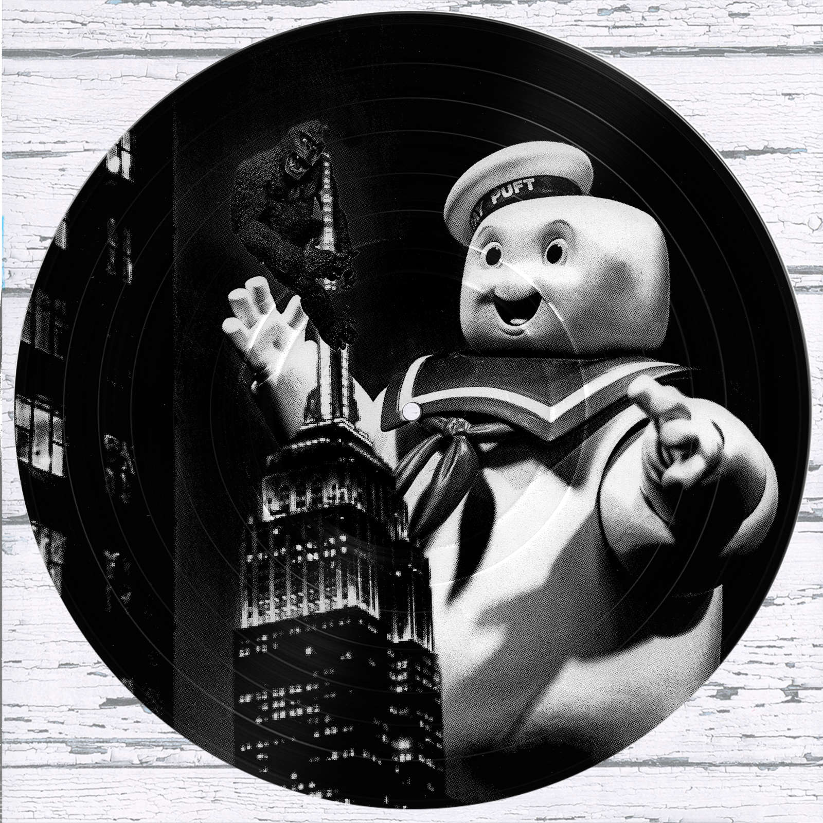 King Kong vs Stay Puft vinyl record photo art featuring a black and white photograph of the Empire State Building at night with King Kong perched on top and Stay Puft Marshmallow Man reaching upward.
