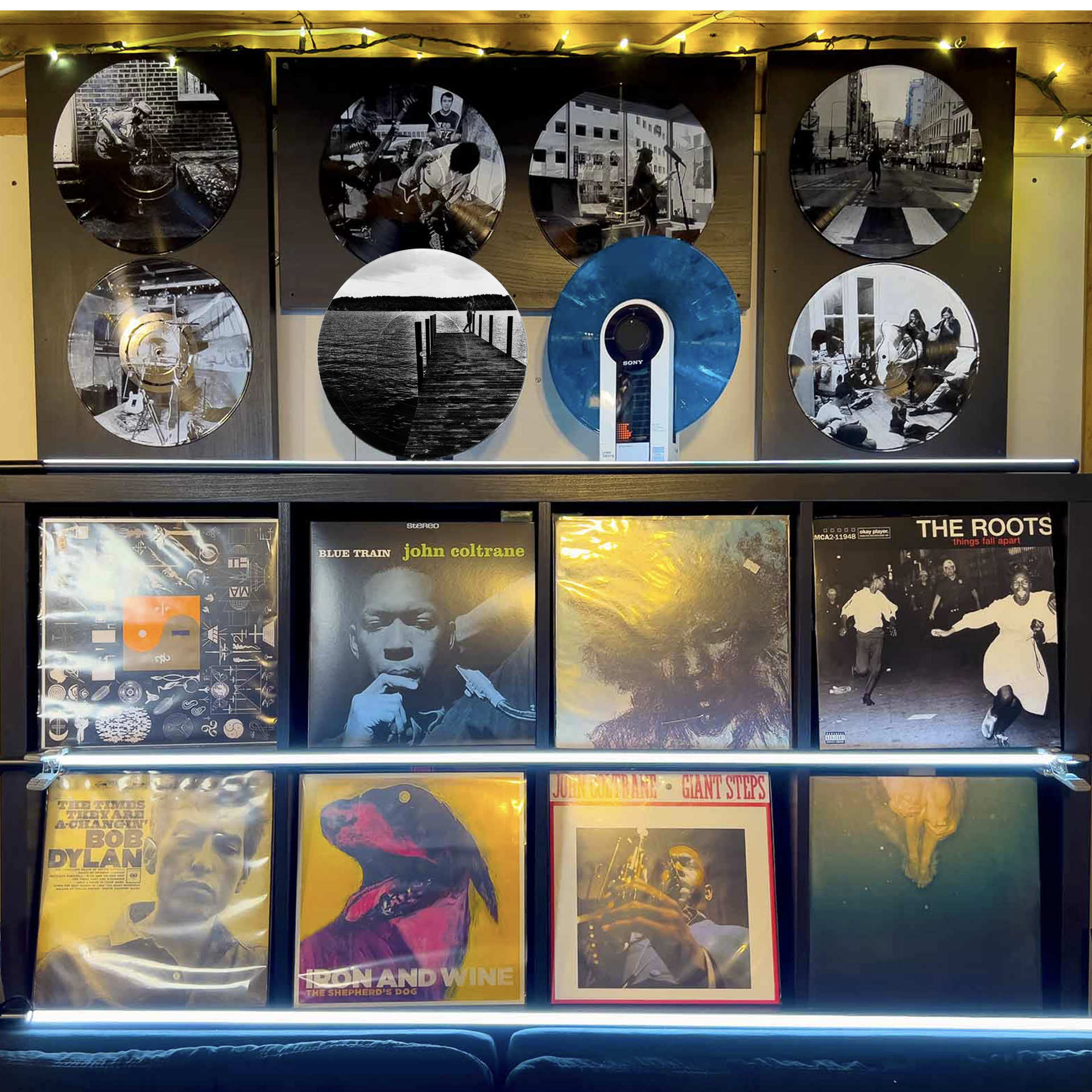Vinyl record photo art featuring a lakeside dock at sunrise, arranged on a gallery wall display.