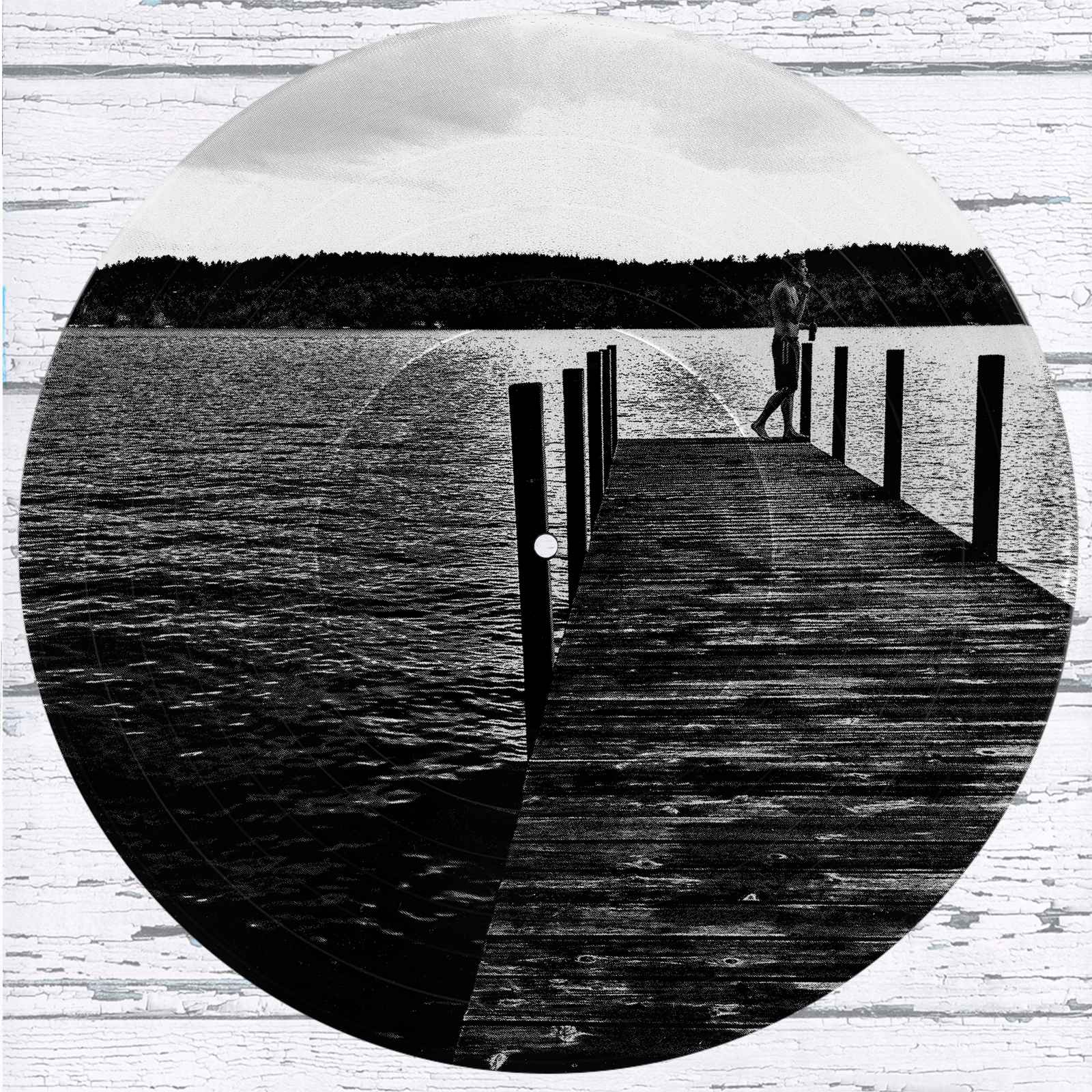 Lakeside Dock vinyl record photo art featuring a black and white photograph of a person on a dock at sunrise over a calm lake.”