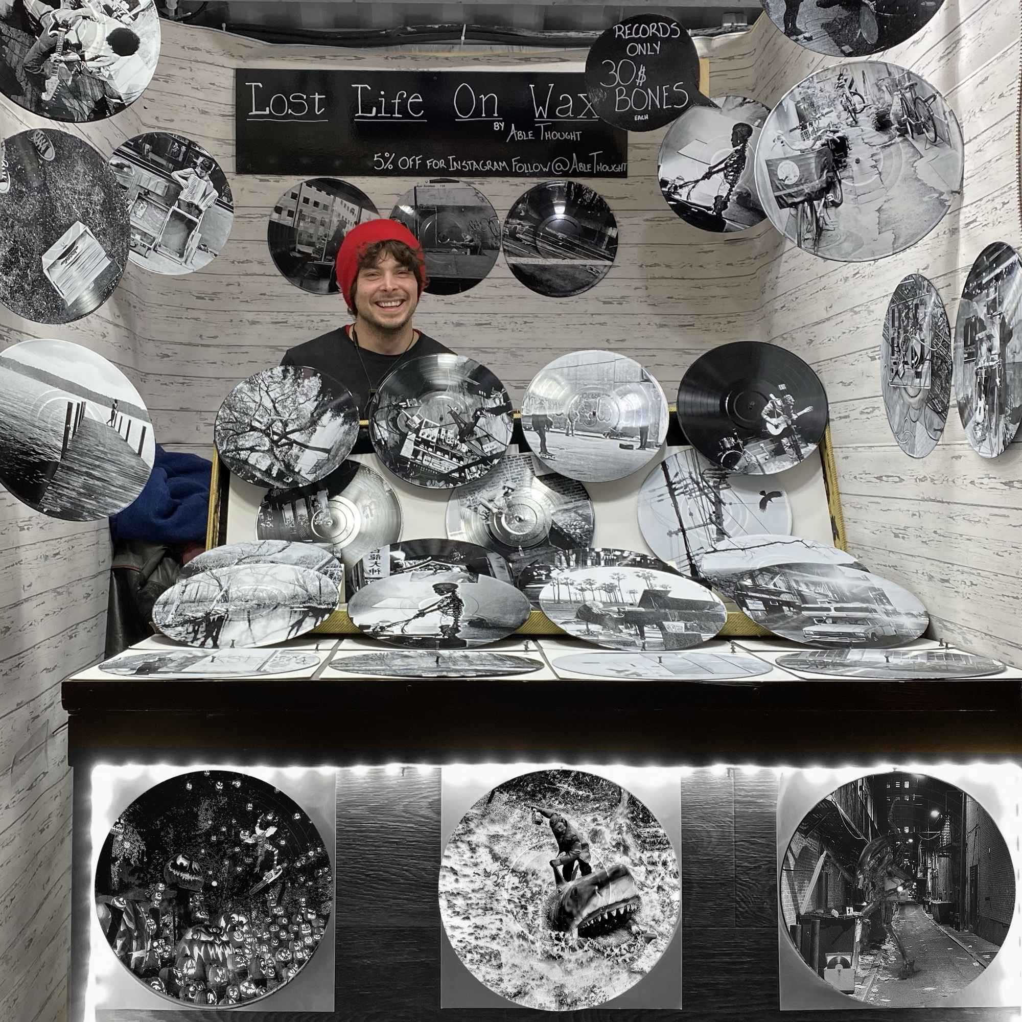 Vinyl record photo art of Quint from Jaws riding Bruce the shark with a six-pack of beer, displayed at an art market booth.