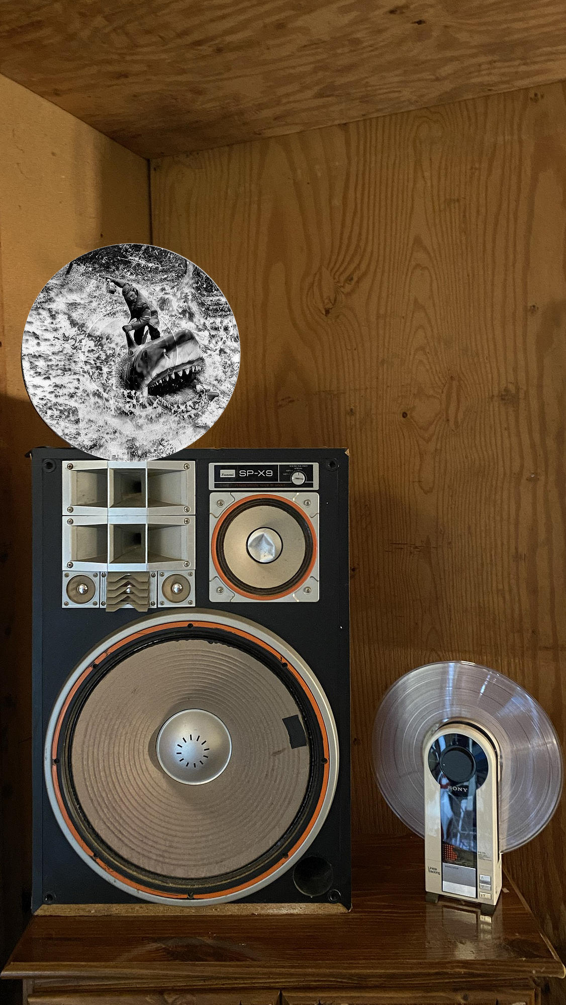 Circular vinyl record wall art of Quint and Bruce the shark from Jaws with a six-pack of Narragansett beer, displayed in a music room.